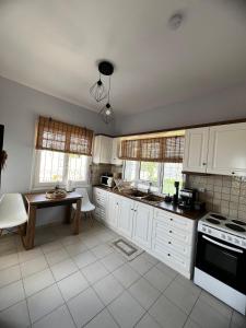a kitchen with white cabinets and a table at Eleni's Seaview House in Saronida