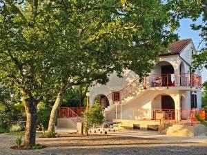 a white building with a balcony and a tree at Villa Kučan in Porat