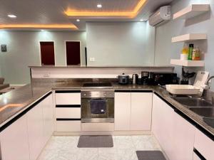 La cuisine est équipée de placards blancs, d'une cuisinière et d'un évier. dans l'établissement Cozy Manor with Spacious Kitchen and Tub, à General Santos 5 autres photos