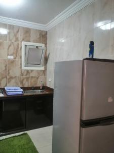 eine Küche mit einem Kühlschrank und einem TV an der Wand in der Unterkunft شاليه محجوب بديمورا in Dawwār Muḩammad Abū Shunaynah + 6 Fotos