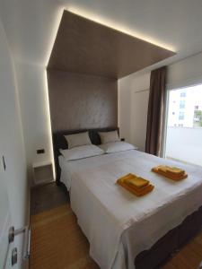 a bedroom with a large white bed with two wooden towels on it at Beach apartments Promajna in Promajna