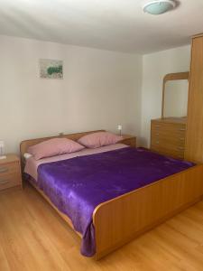 a bedroom with a large bed with a purple blanket at Apartment Anić in Šmrika