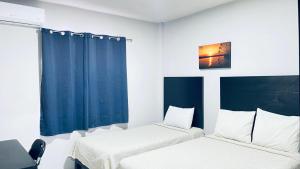 two beds in a room with blue curtains at HOTEL TAMPICO EXPRESS MORALILLO in Tampico