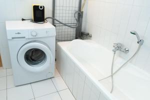 a bathroom with a washing machine and a bath tub at Maison urbaine familiale in Béziers
