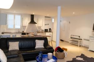 a living room with a black leather couch and a kitchen at Maison urbaine familiale in Béziers