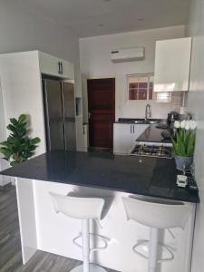 a kitchen with a black counter top and white cabinets at Cozy haven apartments in Paramaribo