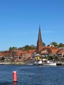 Un barco en el agua cerca de un pueblo con una iglesia. en Ferien Wohnung Katzenruh, en Lauenburgo/Elbe