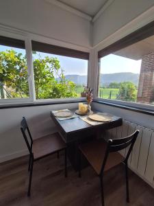 a dining room with a table and two chairs and two windows at Haize Lore Bakio in Bakio +32 photos