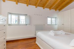 a white bedroom with a bed and two windows at Atena at Como Duomo in Como