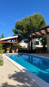 a swimming pool with a pergola and a swimming pool at Pine Tree Villa in Pakoštane