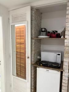 a small kitchen with a microwave on a counter at Villa Buziana 1 in Búzios +2 photos