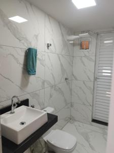 a white bathroom with a sink and a toilet at Minha casa, meu lar! Praia de Jacaraipe ES! in Serra