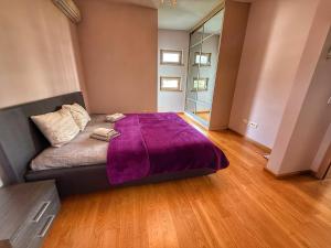 a bedroom with a bed with a purple blanket on it at Jelena apart Budva in Becici