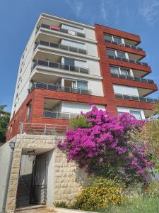 a tall building with purple flowers in front of it at Jelena apart Budva in Becici
