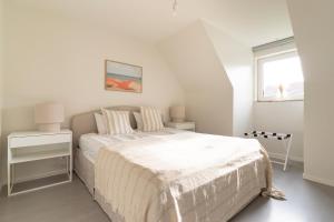 a white bedroom with a bed and a window at Falsterbo Beachside Apartments in Skanör med Falsterbo