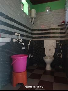 a bathroom with a toilet and a sink and a bucket at Srujana Beach Homestay in Gokarn