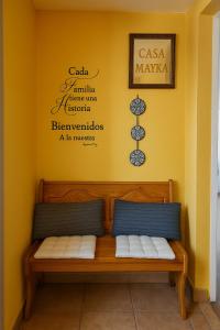 a bench in a room with a yellow wall at Pensión O Muiño in O Pedrouzo