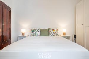 a bedroom with a large white bed with two lamps at Domu Maria in Cagliari +16 photos