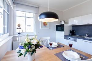 a kitchen with a wooden table with a vase of flowers at Am Horizont No 3 für 2-4 Pers, 2 Schlafz, Garten, Strandkorb, Grill, Parkplatz, am Haus in Zingst +11 photos