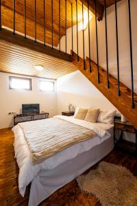 a bedroom with a large bed with a staircase at Планинска вила АЛТЕА in Mostowo