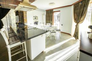 a kitchen with white cabinets and a table and chairs at Планинска вила АЛТЕА in Mostowo +23 photos