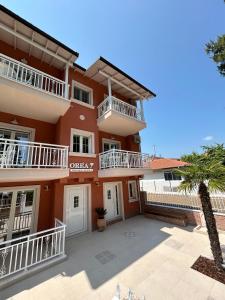 un grande edificio arancione con balconi bianchi e una palma di Orea Boutique Studios a Asprovalta
