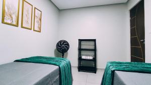 a bedroom with two beds and a black shelf at Casa Luz Caruaru - próx feira da sulanca in Caruaru