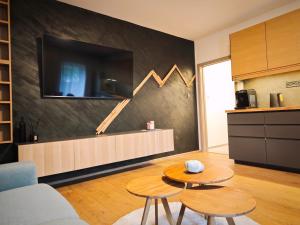 Apartmán 4, Pstruží, Krušné hory في Merklín: غرفة معيشة مع طاولتين وتلفزيون على الحائط