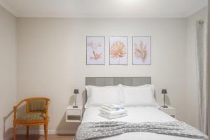 a white bedroom with a bed and a chair at Flórida vivo bem! in São Roque