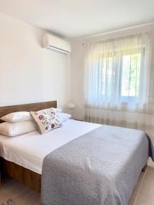 a bedroom with a bed with white sheets and a window at Nada in Krk