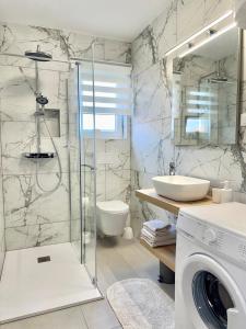 a bathroom with a shower and a sink and a washing machine at Nada in Krk