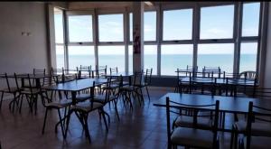 a room with tables and chairs and large windows at Frente al Mar con cochera in Miramar