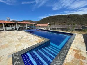 a swimming pool with blue water in front of a house at Chalés Lampião in Piranhas