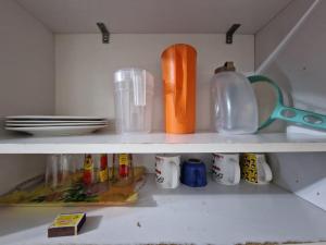 a shelf with dishes and utensils in a kitchen at FLAT CENTRAL- Ar-Condicionado-Estacionamento in Feira de Santana