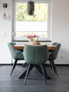 una sala da pranzo con tavolo in legno e sedie verdi di NEU! Forstwald-Haus I Kamin - Netflix - Hot Tub Pool - Düsseldorf a Krefeld