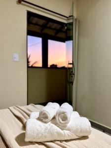 Un grupo de toallas sobre una cama con una ventana. en Pousada Fruto do Mar, en Saquarema