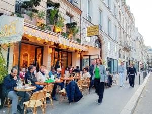 eine Gruppe von Menschen, die an Tischen vor einem Restaurant sitzen in der Unterkunft Le Marais,center ,5 minute Eiffel tour and Louvre meusm ,1 mins metro in Paris + 26 Fotos