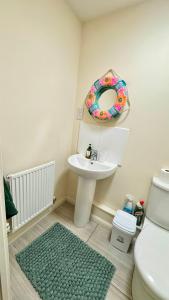 Un baño con lavabo, inodoro y espejo. en Emerald dream house, en Swindon