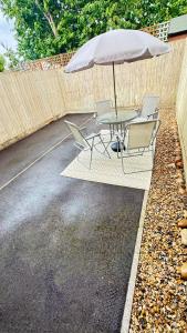 a patio table and chairs with an umbrella at Emerald dream house in Swindon