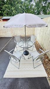 a glass table with two chairs and an umbrella at Emerald dream house in Swindon