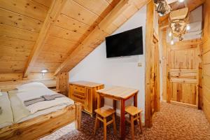 a bedroom with a bed and a desk and a tv at RANČ Podlesok Relax in Hrabušice