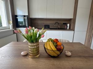 a bowl of fruit and a vase of flowers on a table at Apartman Perla in Gornji Kraj