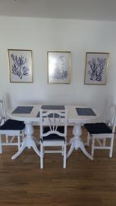 una mesa de comedor blanca y sillas con pinturas en la pared en La Lapa, en Arrecife