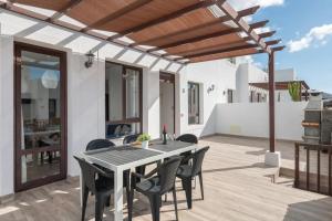 un patio con mesa y sillas bajo una pérgola en Luxury Villa Lanzarote, en Playa Blanca