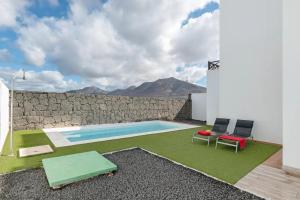 una piscina con dos sillas y una pared de roca en Luxury Villa Lanzarote, en Playa Blanca