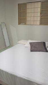 a white bed with a pillow on top of it at Casa quase frente a Rodoviária in Corumbá