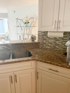 a kitchen with white cabinets and a sink at Quiet direct oceanfront 2 bed 2 bath condo w/pool in Ormond-by-the-Sea