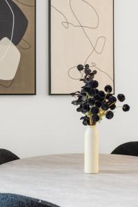 eine weiße Vase mit Blumen auf einem Tisch mit Gemälden in der Unterkunft Stylish NYC Haven Steps to Broadway & Dining in New York + 10 Fotos