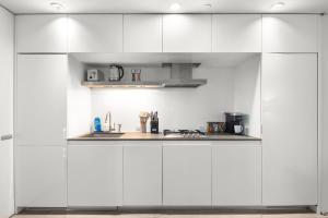 eine Küche mit weißen Schränken und einer Spüle in der Unterkunft Stylish NYC Haven Steps to Broadway & Dining in New York