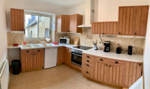 a kitchen with wooden cabinets and a white appliance at Beaumont Vélo le Gîte in Beaumont-sur-Sarthe